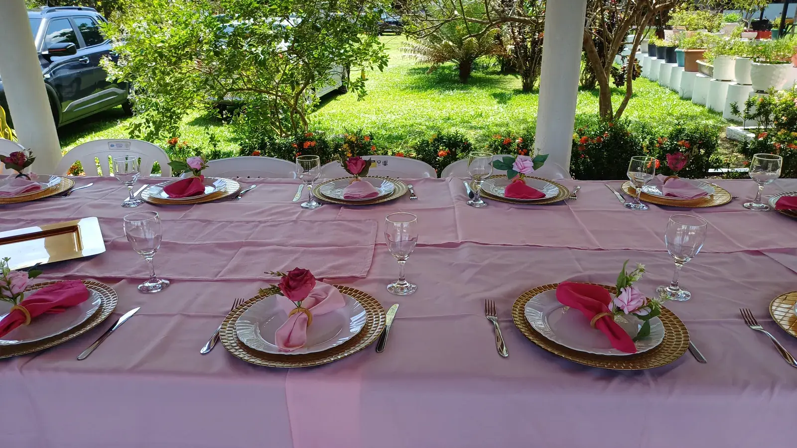 Mesa comprida posta com toalha rosa e pratos dourados